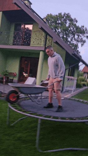 a man pushing a wheelbarrow on a trampoline