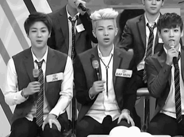 a group of young men in suits and ties are holding microphones