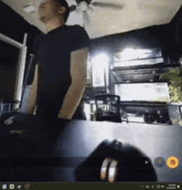 a man in a black shirt is standing in front of a computer monitor