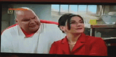 a tv screen shows a man and a woman with the number 12 on the bottom right