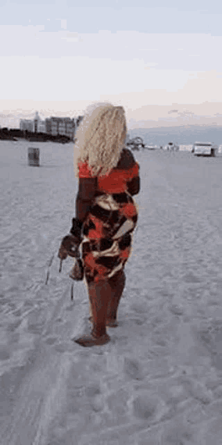 a woman is standing on a beach holding a purse and smiling .