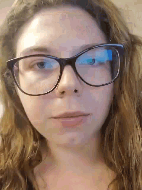 a close up of a woman wearing glasses and looking at the camera .