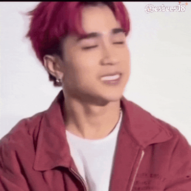a close up of a man with red hair wearing a red jacket and a white shirt .