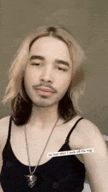 a man with blonde hair and a beard is wearing a black tank top and a necklace .