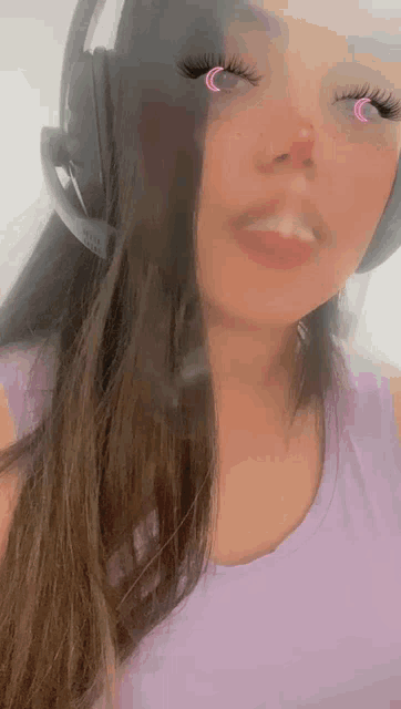 a woman wearing headphones and a purple shirt looks at the camera .