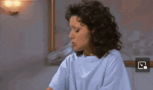 a woman with curly hair is wearing a hospital gown and a blue shirt