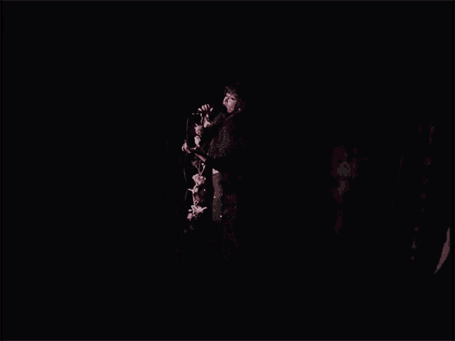 a woman singing into a microphone with flowers in her hand