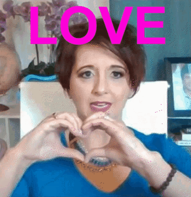 a woman is making a heart shape with her hands and the word love is above her