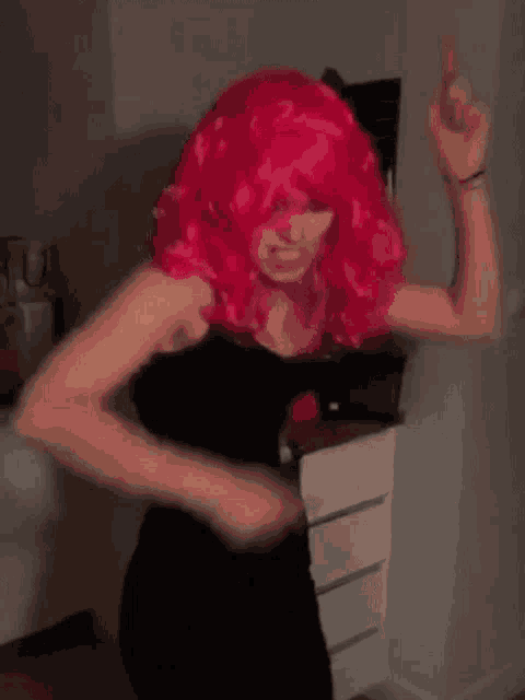 a woman wearing a pink wig is dancing in a room