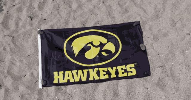 a hawkeyes flag is laying on the sand