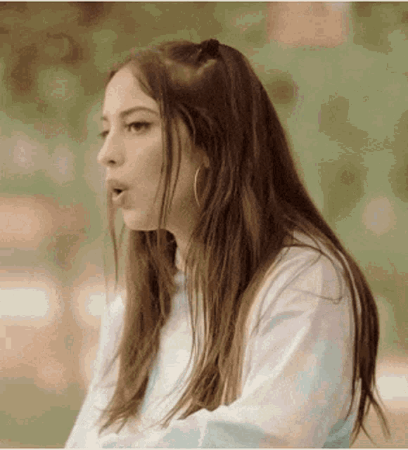 a woman with long hair is wearing hoop earrings and a tie dye shirt .