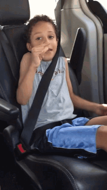 a young boy is sitting in a car seat with a seat belt on