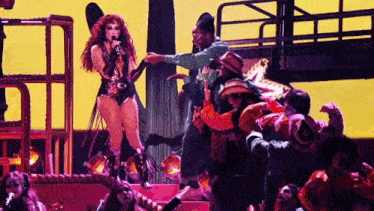 a woman singing into a microphone surrounded by people in cowboy costumes