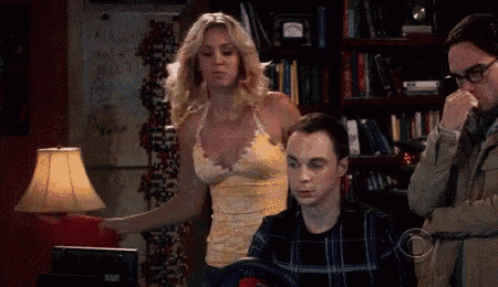 a woman in a yellow top is standing next to a man in a plaid shirt in front of a computer .
