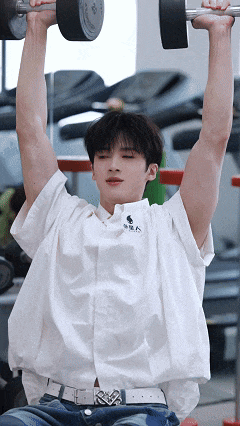 a young man is lifting a dumbbell in a gym