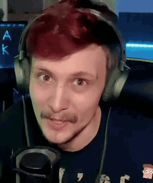 a man with red hair and a mustache is wearing headphones and a microphone .