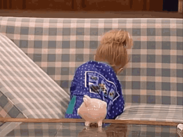 a little girl is sitting on a couch with a piggy bank on the table