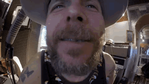 a man with a beard is wearing a hat and a tank top with a butterfly tattoo
