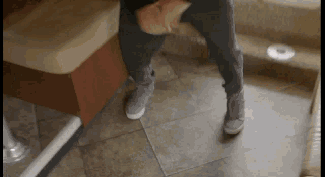a person standing on a tiled floor with their feet up