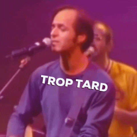 a man is playing a guitar and singing into a microphone while another man stands behind him .
