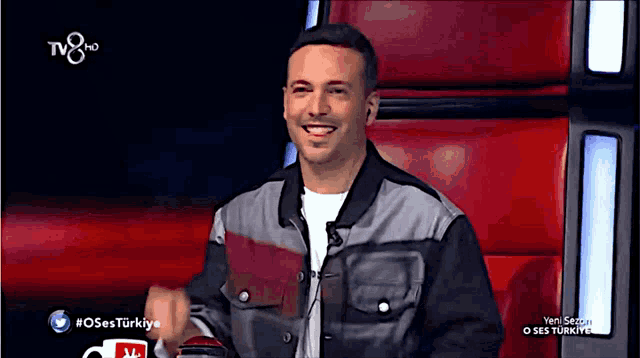 a man is smiling in front of a screen that says tv 8 hd