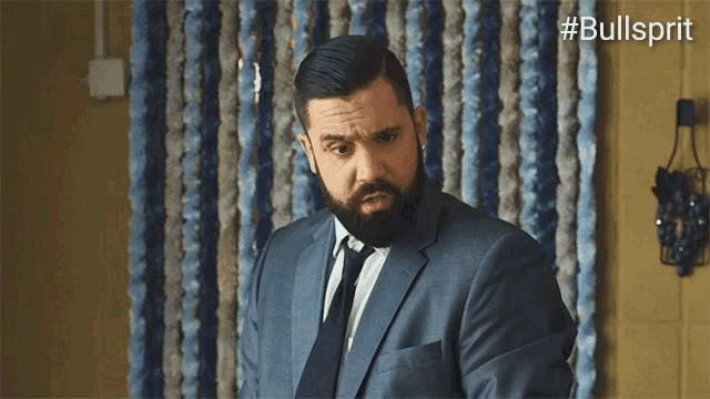 a man in a suit and tie is standing in front of a blue and white curtain ..