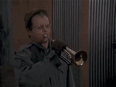 a man in a military uniform is playing a trumpet with a bullet flying through his glasses