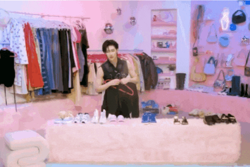 a man is standing in front of a table full of clothes and shoes