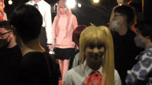 a woman in a pink hoodie stands in a crowd