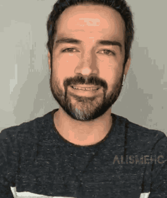 a man with a beard and headphones is smiling for the camera .