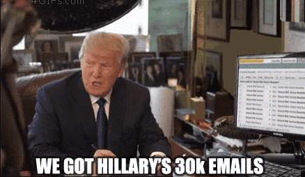 a man in a suit and tie is sitting in front of a computer and says we got hillary 's 30k email