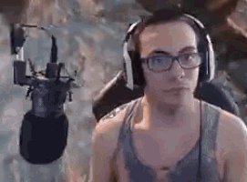 a man wearing headphones is sitting in front of a microphone .