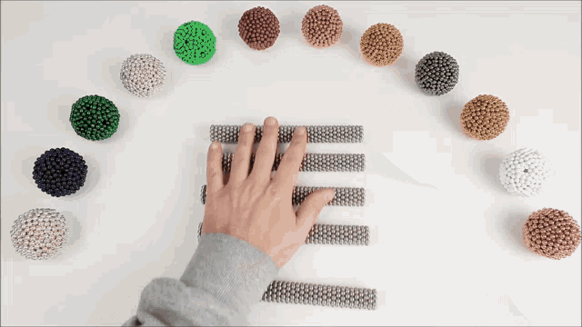 a person 's hand is touching a row of magnetic balls in a circle
