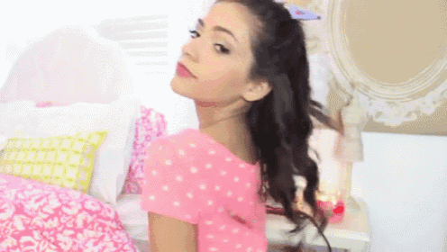a girl in a pink polka dot shirt is standing on a bed