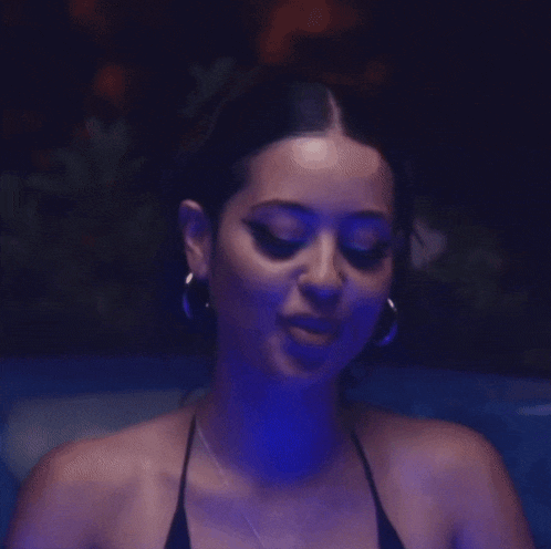 a woman with long nails is wearing a black bikini top and earrings