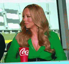 a woman in a green shirt is sitting at a table with a red coca cola cup