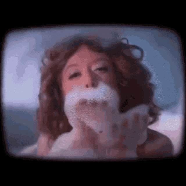 a woman is blowing soap bubbles out of her mouth while sitting in a bathtub .