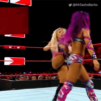 a woman with purple hair is kicking another woman in the ring .
