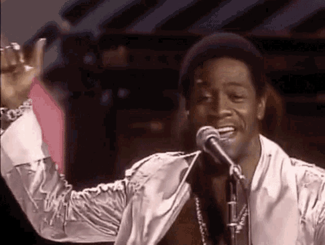 a man is singing into a microphone and giving a thumbs up sign .