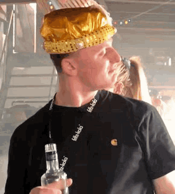 a man wearing a crown is holding a bottle of liquor .