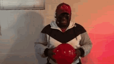 a man wearing a red hat is holding a red balloon in his hands .