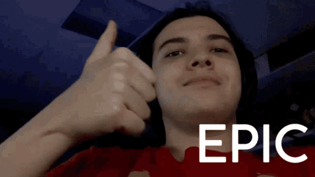 a young man giving a thumbs up in front of a sign that says epic