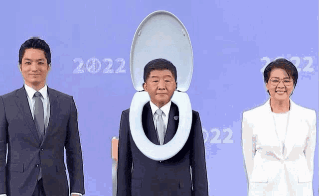 a man in a suit with a toilet seat on his head stands next to two other people .