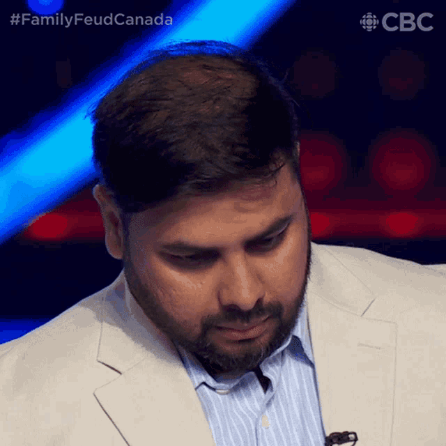 a man with a beard and a white suit is on a television show called family feud canada
