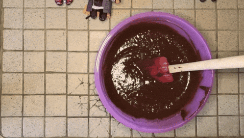 a purple bowl filled with chocolate sauce with a spatula in it