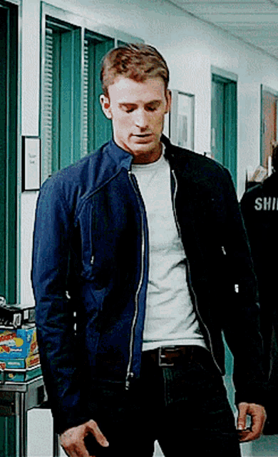 a man in a blue jacket is standing in a hallway with the word shii on his back