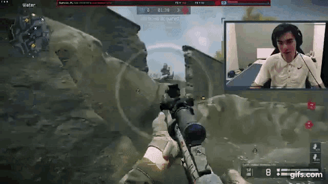 a man is playing a video game while wearing headphones and holding a rifle .
