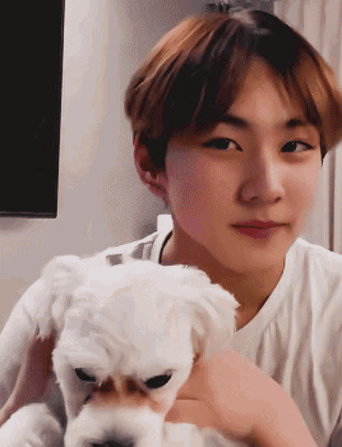 a man is holding a small white dog in his arms