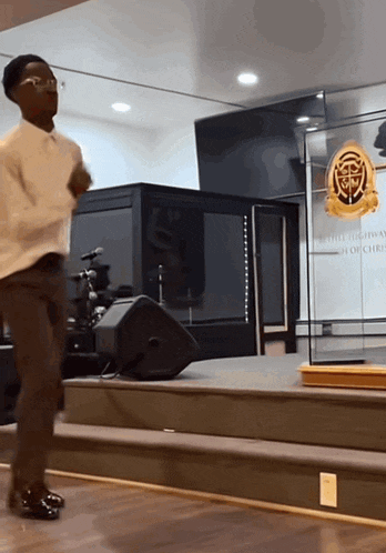 a man stands on a stage in front of a podium that says ' church of christ ' on it