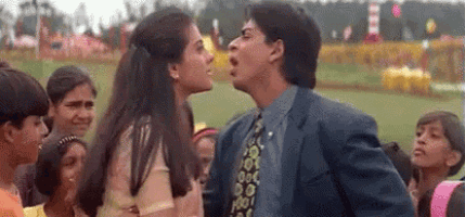 a man in a suit and tie is kissing a woman in front of a crowd of people .